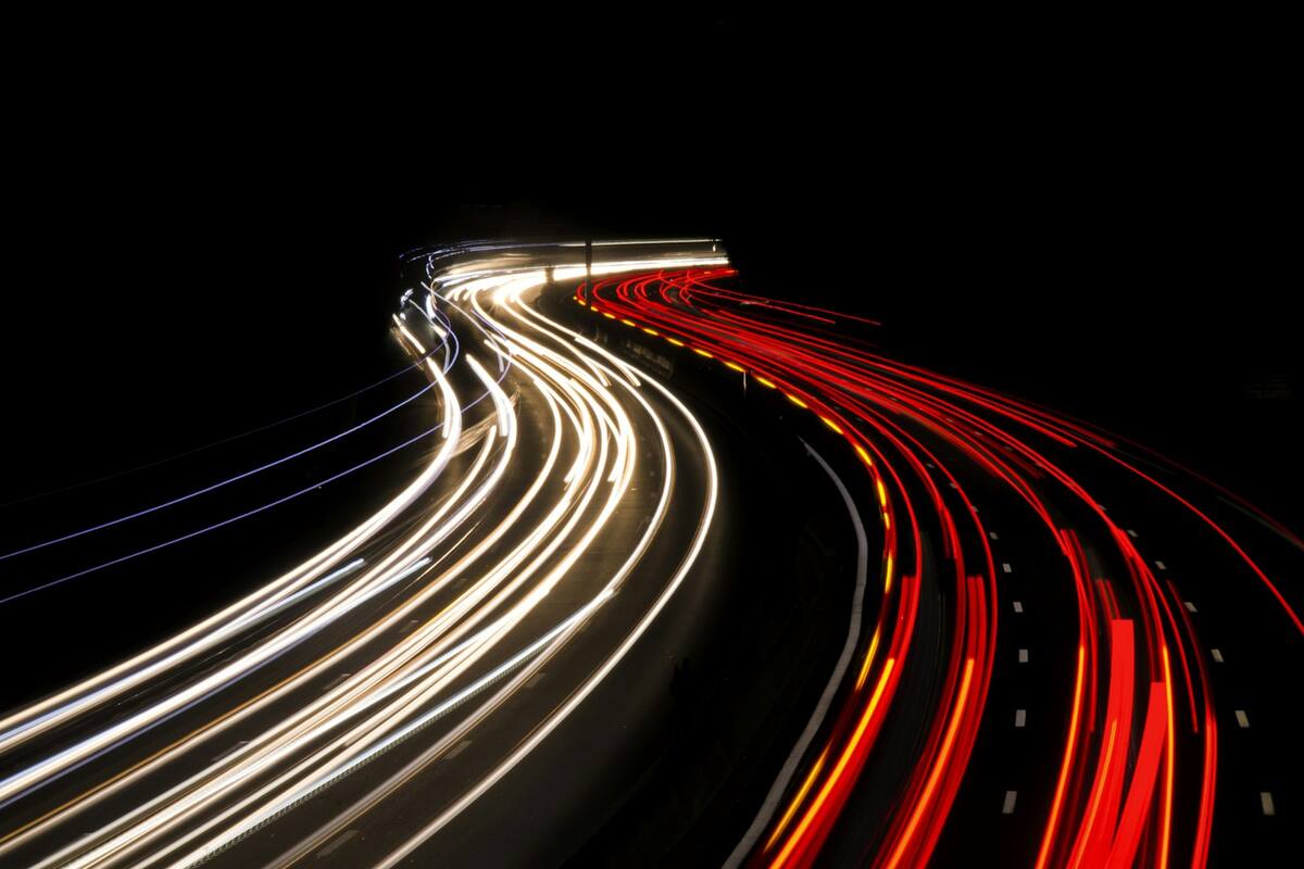 Long-exposure light trails sweeping around a bend at night