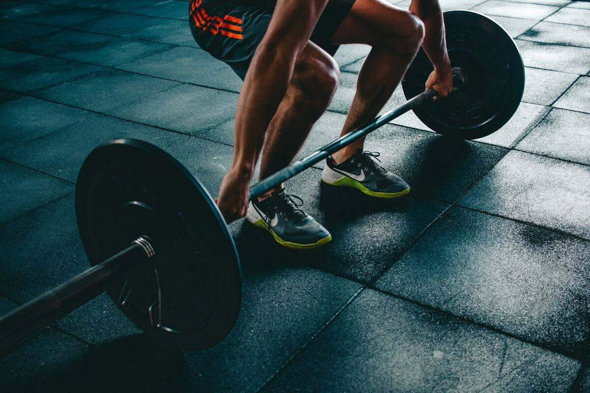 An athlete gripping a loaded barbell on a gym floor